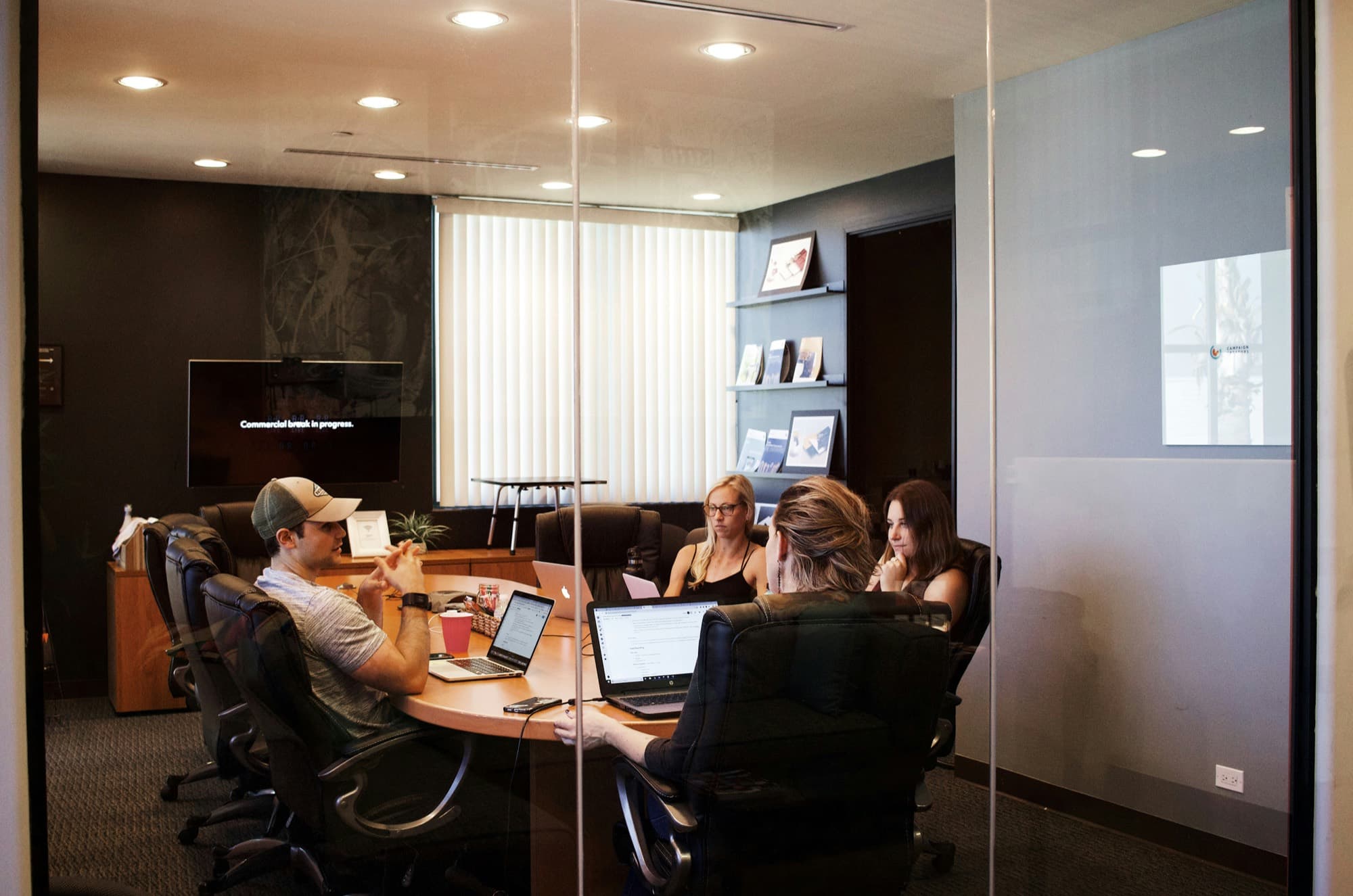 A team meeting around a table with laptops