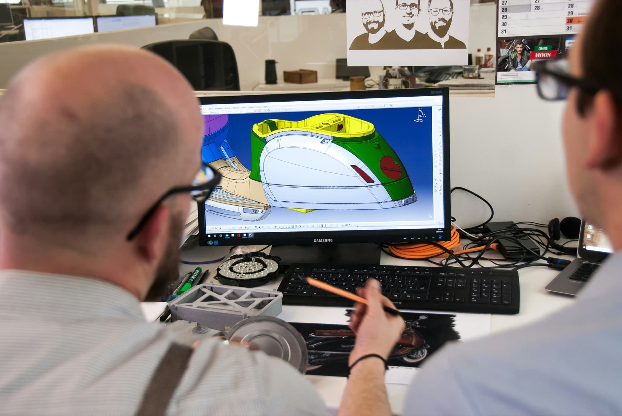 Two designers reviewing a 3D product model on screen